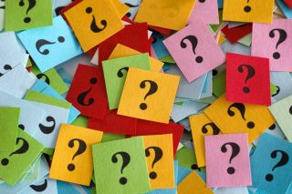 Pile of colorful paper notes with question marks. Close-up.