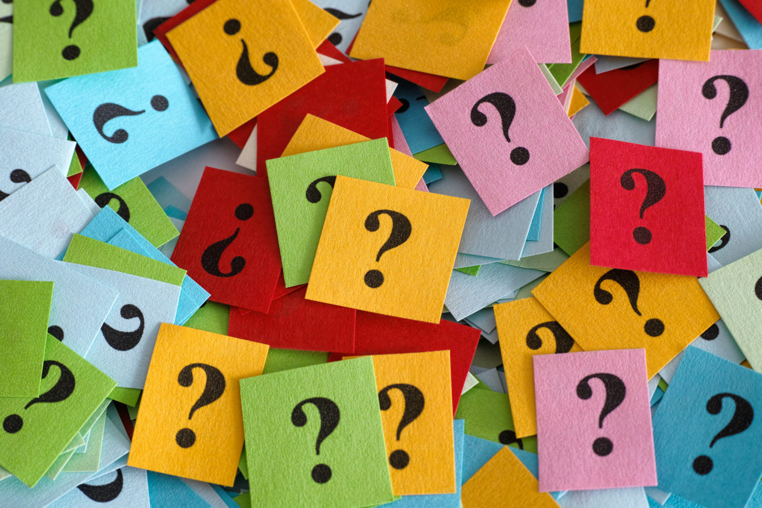 Pile of colorful paper notes with question marks. Close-up.
