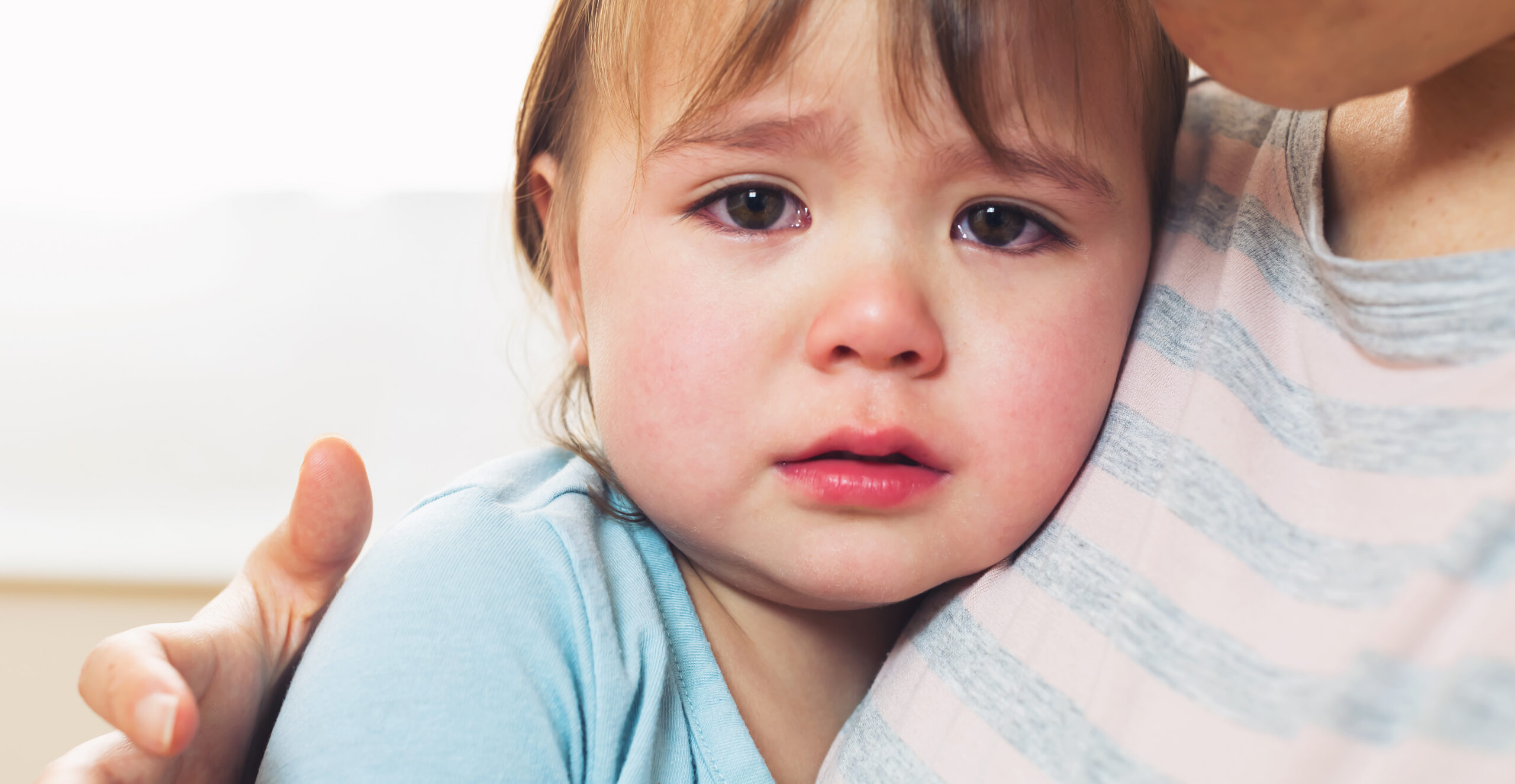 Crying toddler girl being consoled by her mother