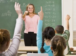 Eager students with their hands raised ready to answer teacher question