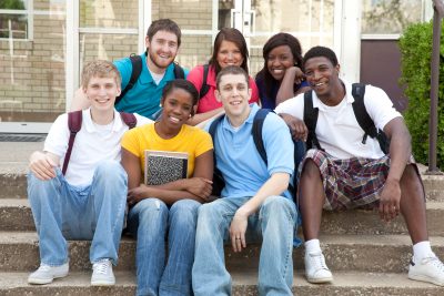 diverse youth sitting on a schools concrete steps