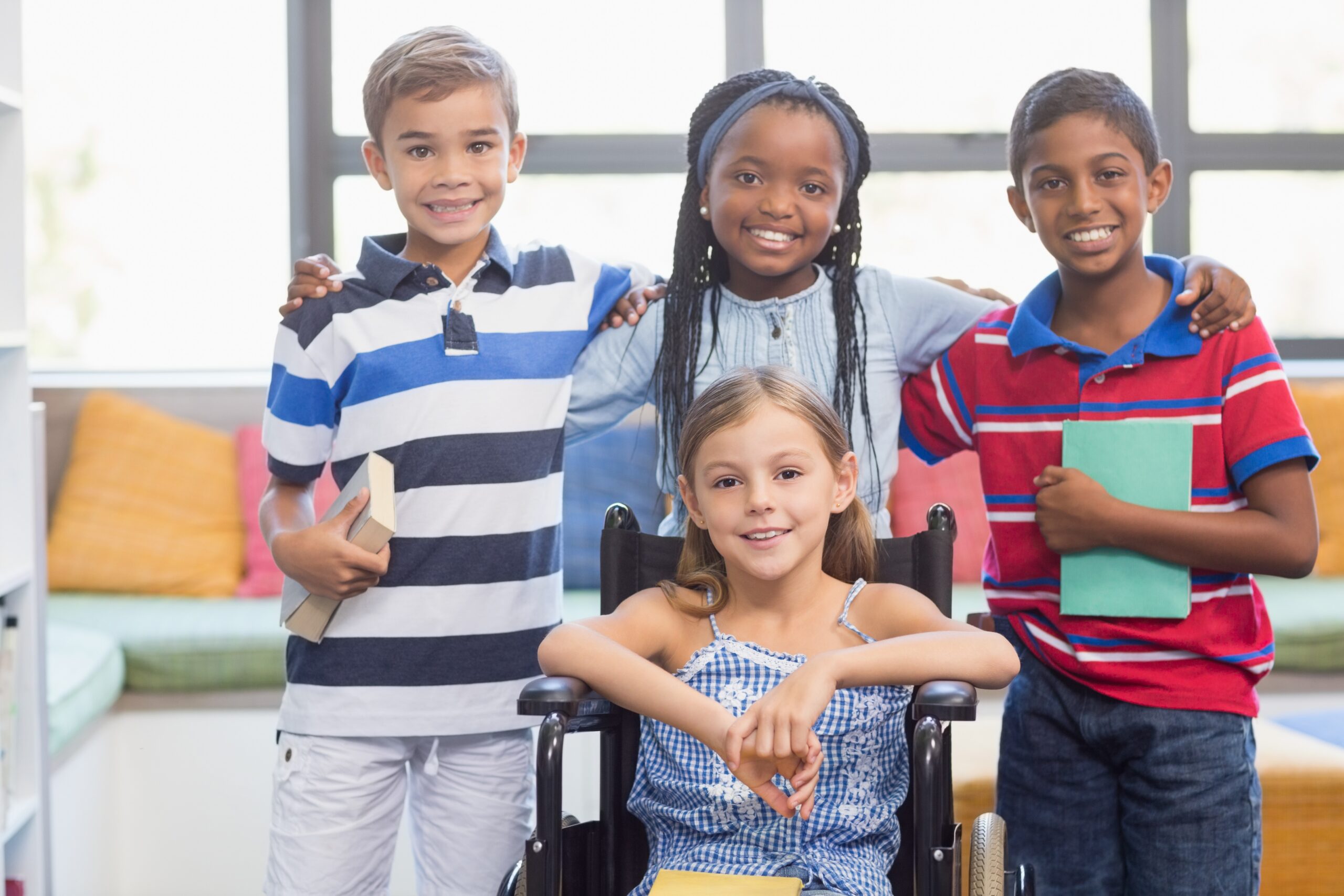 Smiling school kids standing with arm around in library