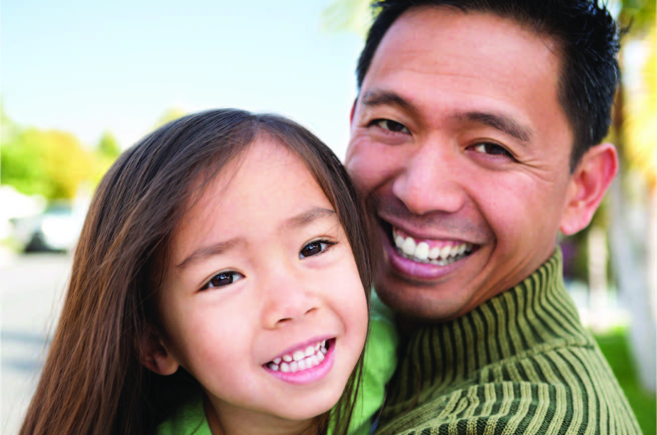 Dad poses and smiles outdoors with Daughter