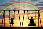 Happy child is a person in a wheelchair riding an adaptive swing next to a typical child together. Concept of adaptive equipment for children with disabilities