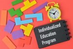 Colorful wooden blocks, clock and notebook written with INDIVIDUALIZED EDUCATION PROGRAM