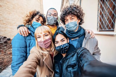 Multiracial friends covered by face mask taking selfie wearing masks