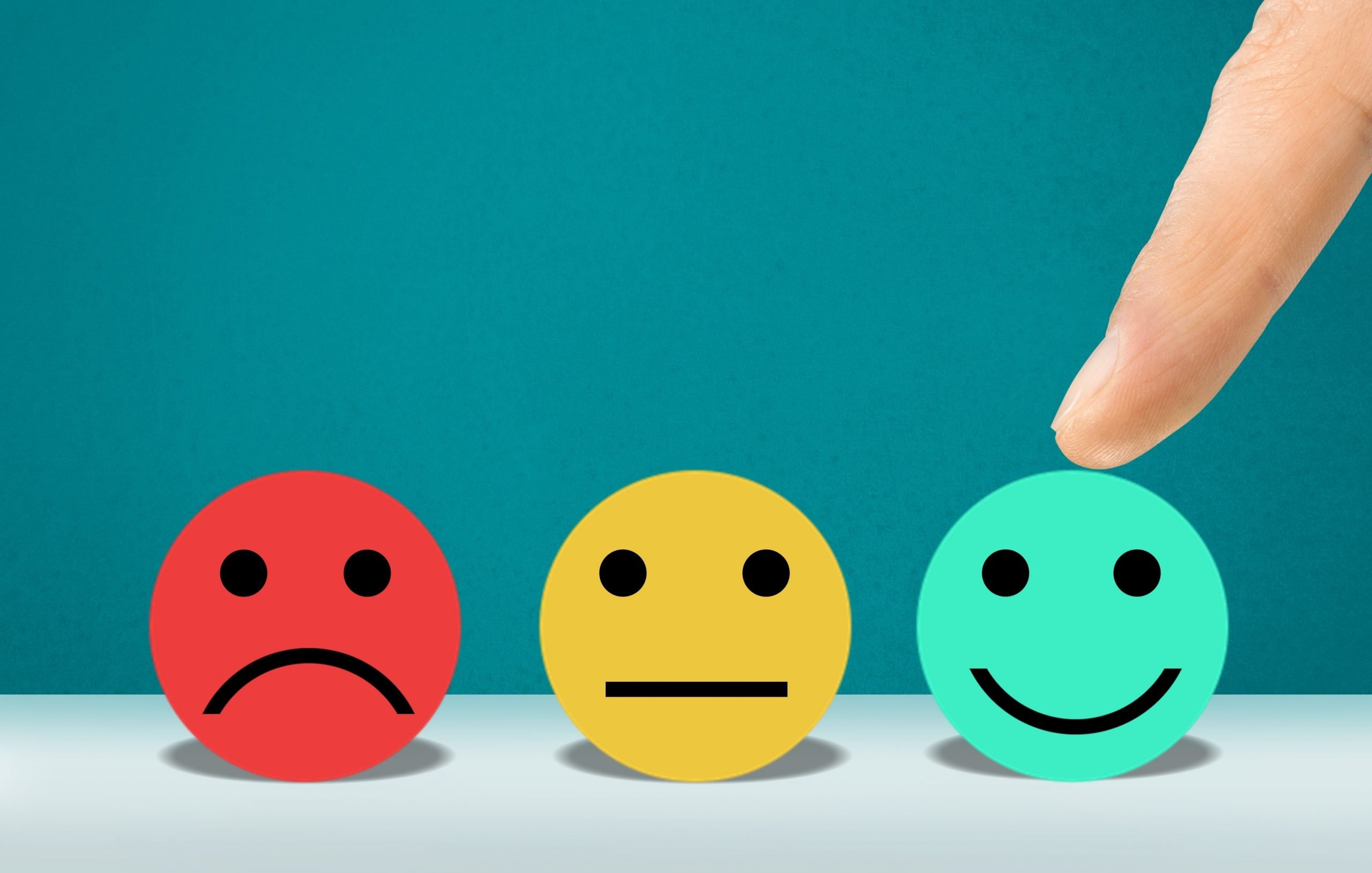 A drawing of three faces are displayed, a sad, indifferent and a happy face, a finger points at the happy face