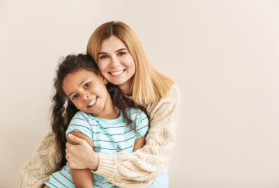 Mom hugging daughter against a solid background