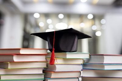 A stack of books with a graduation cap on top. Campus concept