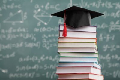 A stack of books with a graduation cap on top. Campus concept