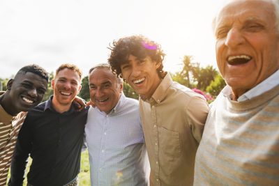 Multi generational men smiling in front of camera - Male multiracial group having fun together outdoor