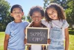 Summer camp, portrait or children with board in park together for fun, bonding or playing in outdoors. Sign, diversity or happy young best friends smiling or embracing on school holidays outside.