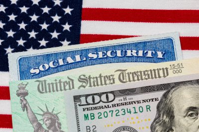 Social security card, treasury check, 100 dollar bill and American flag. Concept of social security benefits payment, retirement and federal government benefits