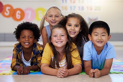 Education, portrait or happy children in classroom learning or smiling in preschool together with support. Kids development, diversity or students with growth mindset for knowledge in kindergarten.