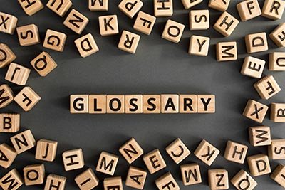 Glossary - word from wooden blocks with letters, alphabetical list with words meanings dictionary glossary concept, random letters around, top view on grey background