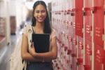 Portrait of a teenage girl standing next to his locker at high school.