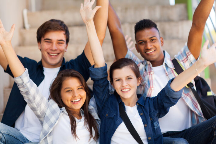 excited high school students with arms outstretched