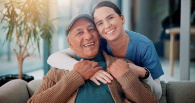 Portrait, nurse and hug old man in home for support, community care and geriatric wellness. Senior patient, happy caregiver and embrace for medical healthcare, assisted living and retirement together.