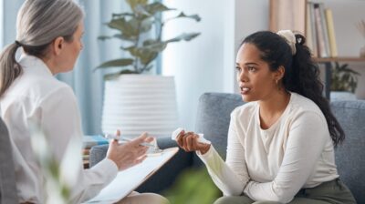 female doctor and young woman seated opposite one another, they are talking