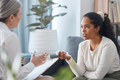 female doctor and young woman seated opposite one another, they are talking
