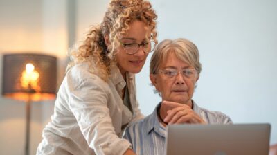 Senior White woman and younger White woman look at laptop together