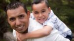 Hispanic man with young boy carried on his back
