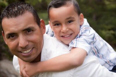 Hispanic man with young boy carried on his back